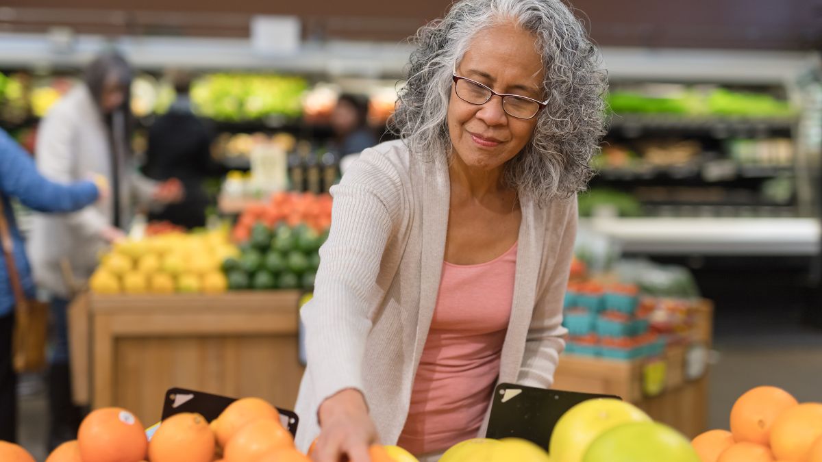 A middle-aged woman shops for produce at a grocery store