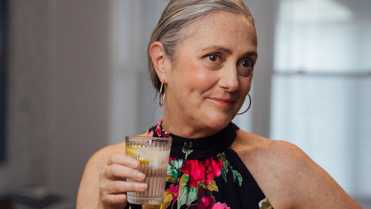 A festively dressed Lynn Folkman drinks a glass of sparkling water.