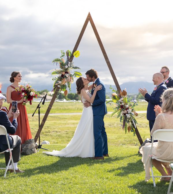 Bethany Adair marries her husband in an outdoor wedding ceremony under a simple wood arch.