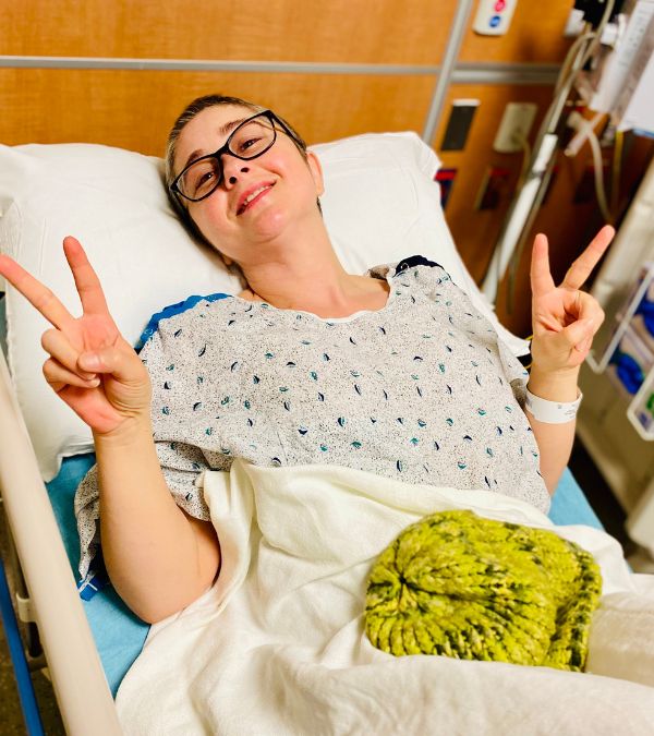 Jenna gives the peace sign in a hospital stretcher.