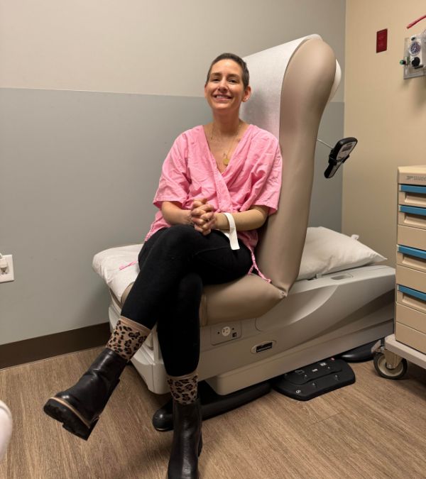 Shannon Gottesman sits in an examining room chair, looking relieved and smiling.
