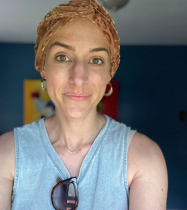 Shannon Gottesman looks thoughtful as she wears a neutral-colored headwrap.