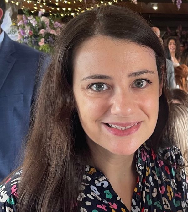 Margalit Tepper smiles confidently as she wears a vibrant blouse with a graphic pattern.