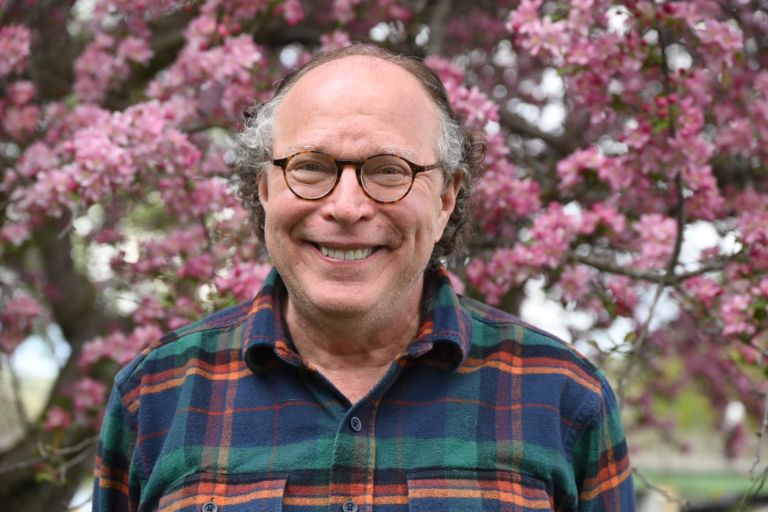 Bob Riter stands happily before cherry blossoms in bloom.
