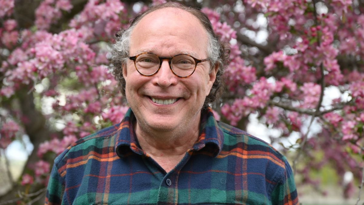 Bob Riter stands happily before cherry blossoms in bloom.