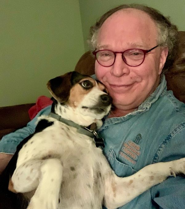 Bob Riter sits cuddling his dog, a beagle, in his lap.
