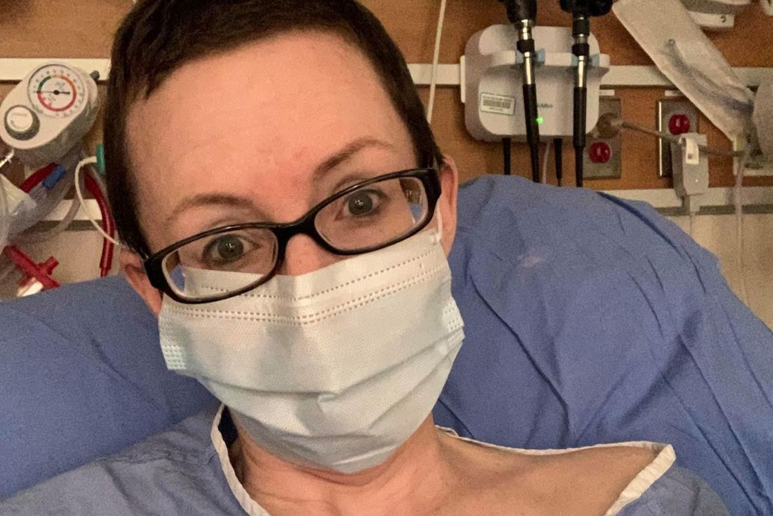 Julie Rock wears a surgical mask, her hair shorn.