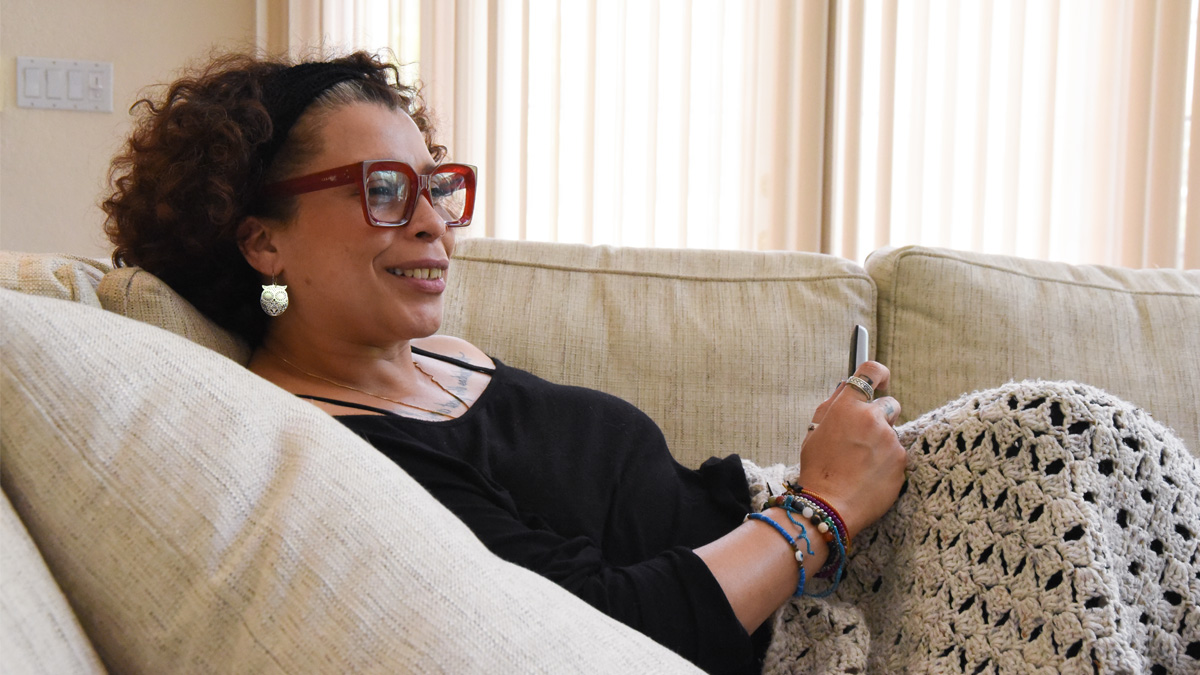 A latina woman smiling, laying on a couch.