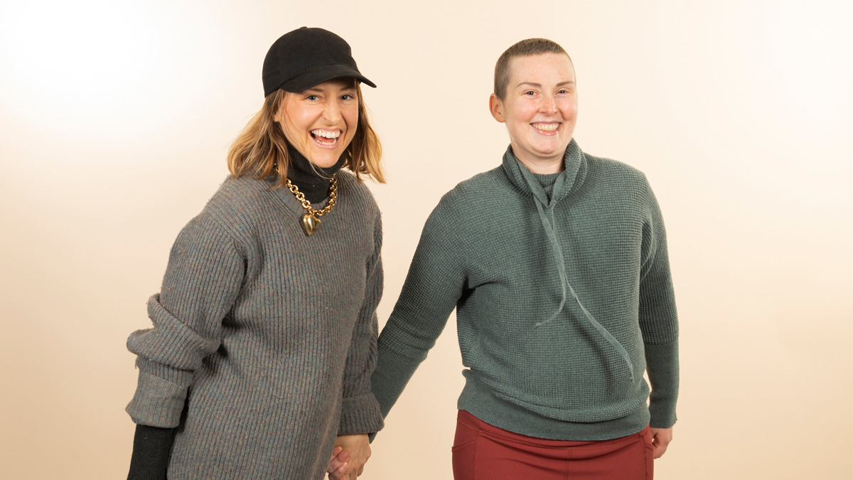 Two white woman holding hands and smiling.