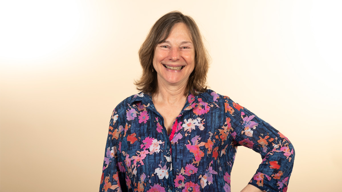 A white woman smiling, with her hand on her hip.