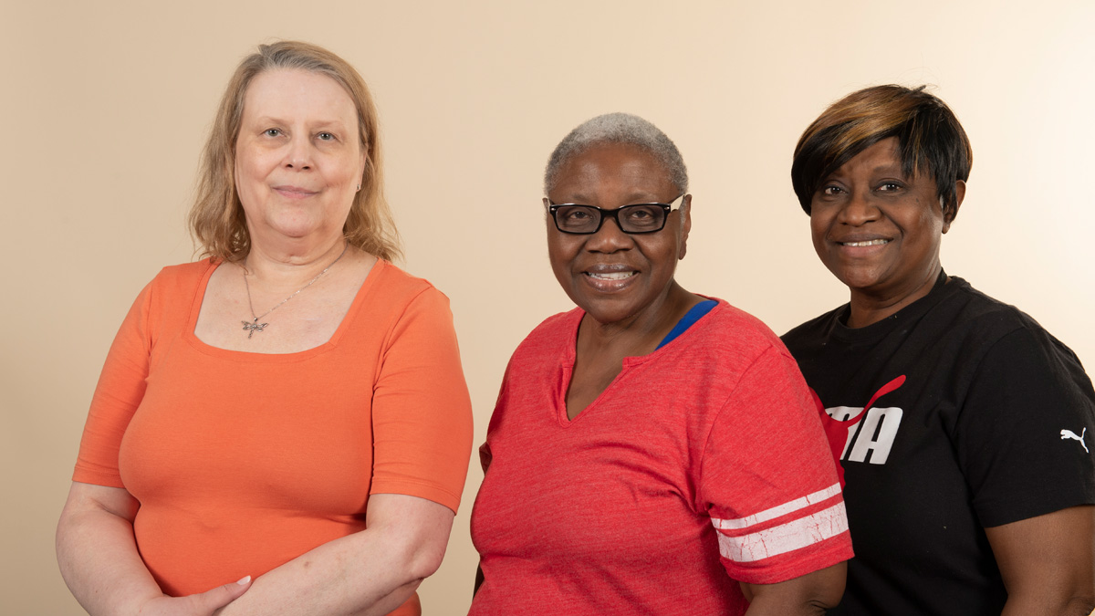 Three older woman; one white and two Black, posing together.