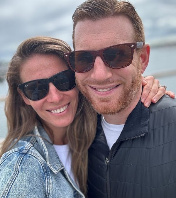 Karen Powell and her husband are wearing sunglasses, their affection for each other evident by their physical closeness, in this selfie.