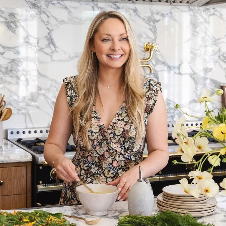 Chloe-Charlotte Crampton in the kitchen smiling while mixing food in a bowl.