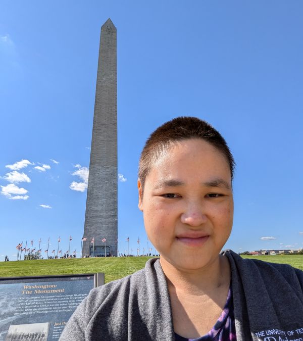 Christina Jue sightsees in Washington, D.C., the Washington Monument behind her.