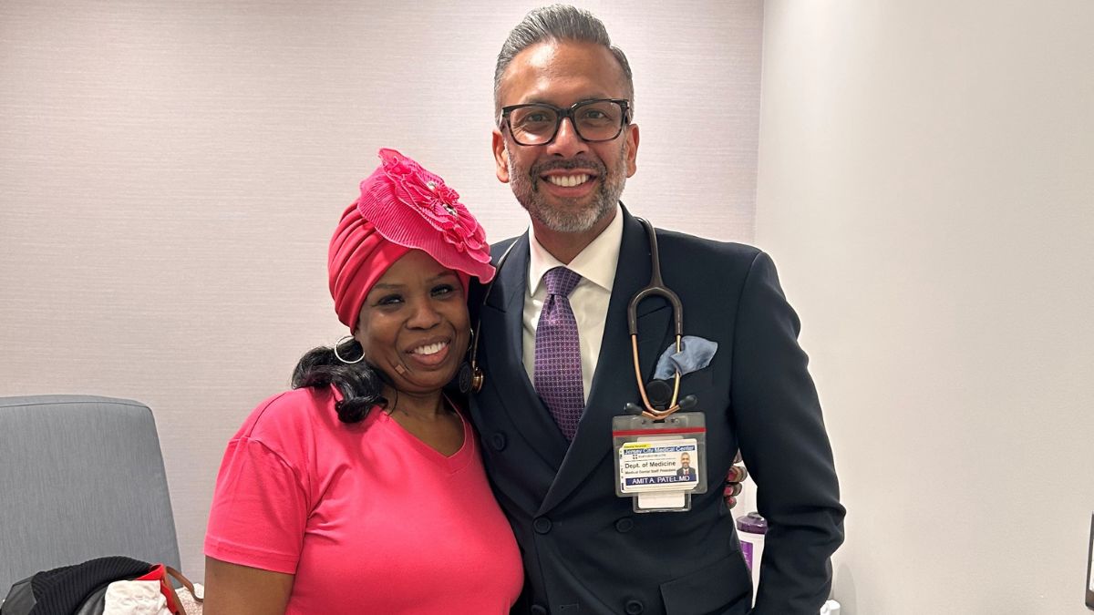 La-Trenda Ross stands confidently with her tailored-suit-wearing oncologist.