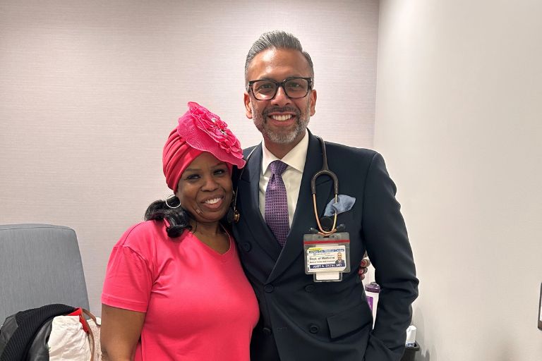 La-Trenda Ross stands confidently with her tailored-suit-wearing oncologist.