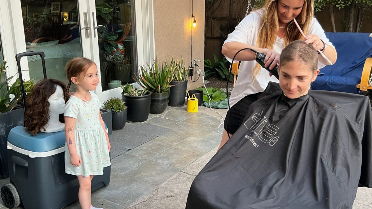 Lilly Ribner's four-year-old daughter watches as her mom has her hair shorn in preparation for chemotherapy.