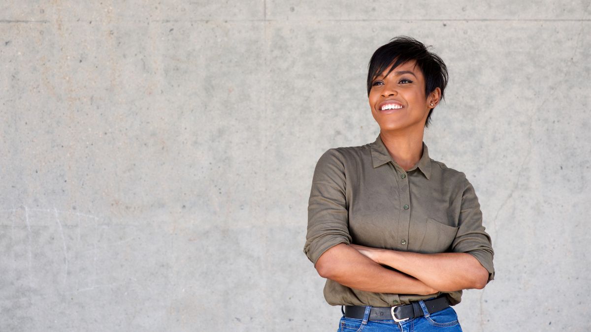 A Black woman smiling with her arms crossed.