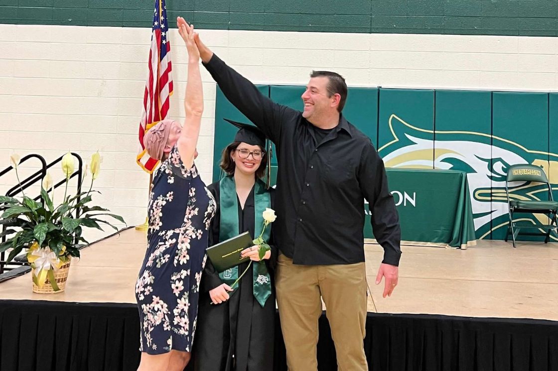 Klara Hartfiel and her husband clap a high five above their graduating daughter's head.