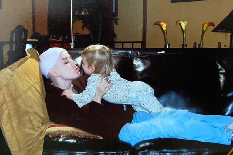 Klara Hartfiel kisses her baby daughter as she rests on the couch during her breast cancer treatment.