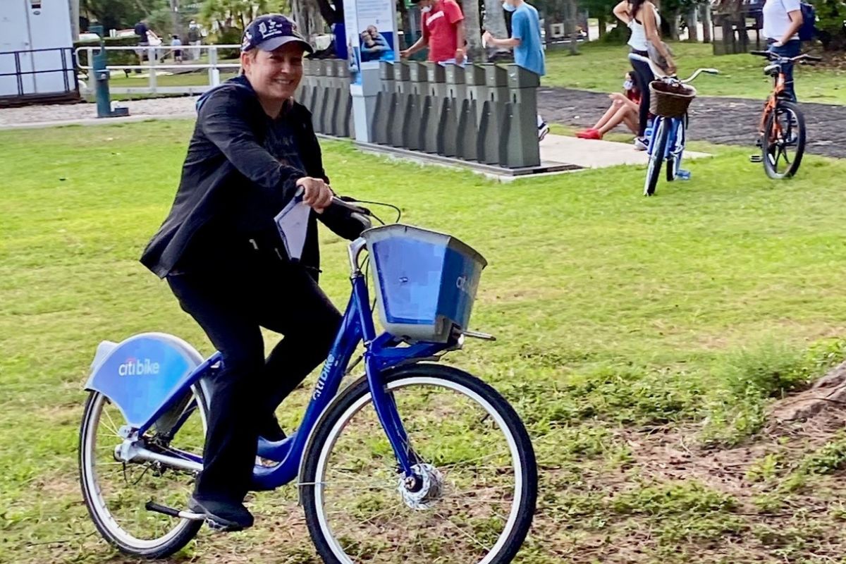Maria Lleonart happily rides a bike in the park.
