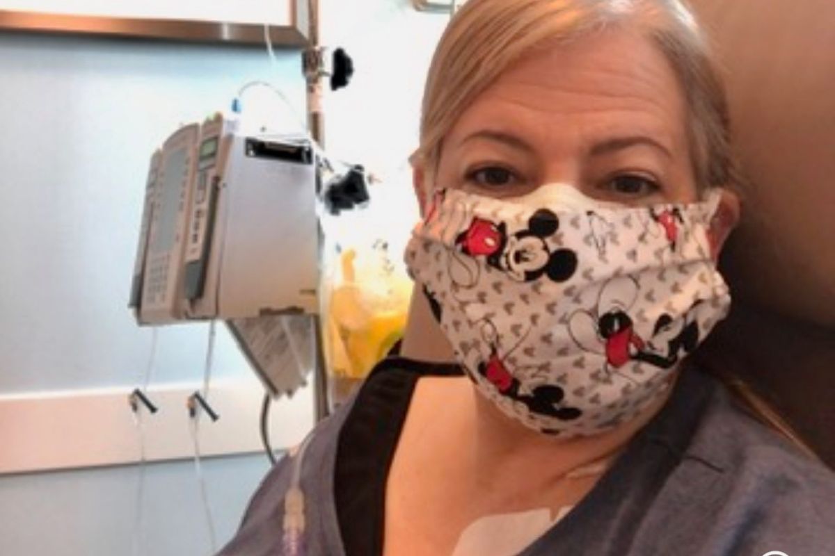 Maria Lleonart documents her first chemotherapy treatment by taking a selfie of herself, masked, the IV stand by her side.