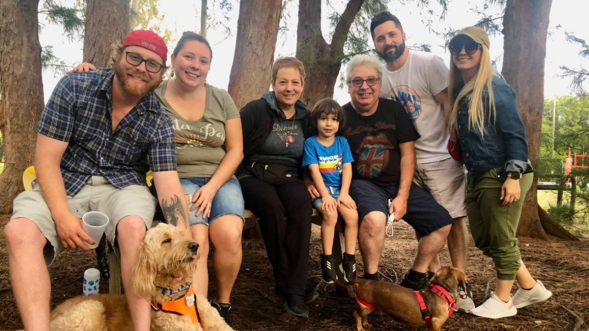 Maria Lleonart and her family huddle close in a beautiful park, surrounded by tall trees.