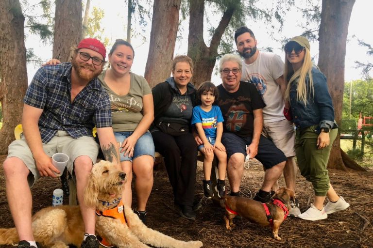 Maria Lleonart and her family huddle close in a beautiful park, surrounded by tall trees.