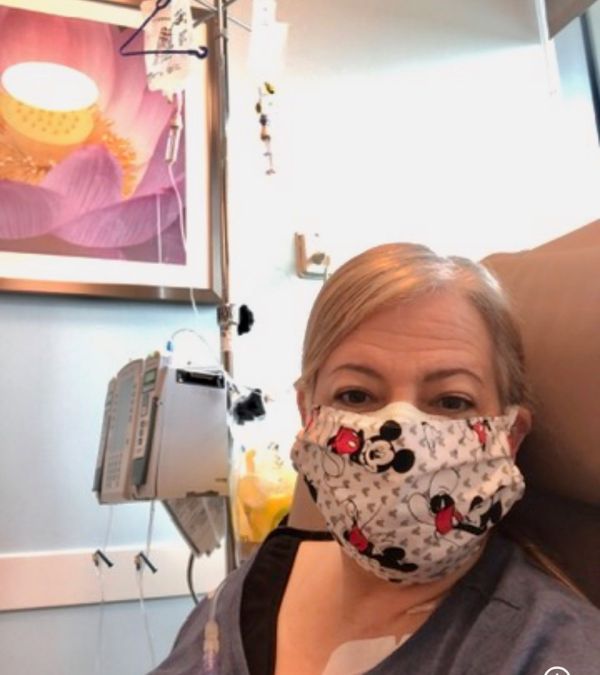 Maria Lleonart documents her first chemotherapy treatment by taking a selfie of herself, masked, the IV stand by her side.