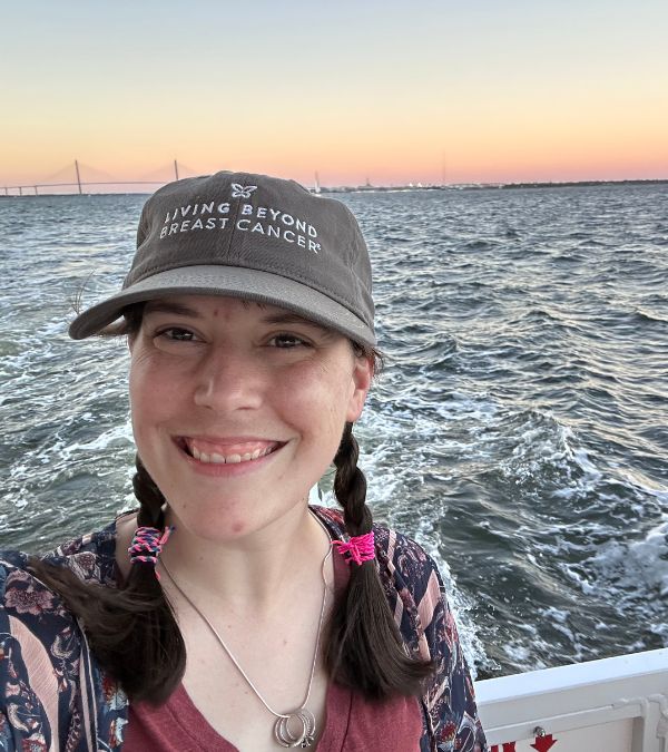 Molly Gaynor takes a selfie with a tangerine slushie sunset at the horizon and an ocean of rippling waves behind her.