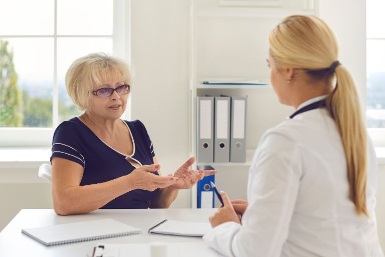 A woman calmly asks her doctor questions as they meet in the doctor's office.