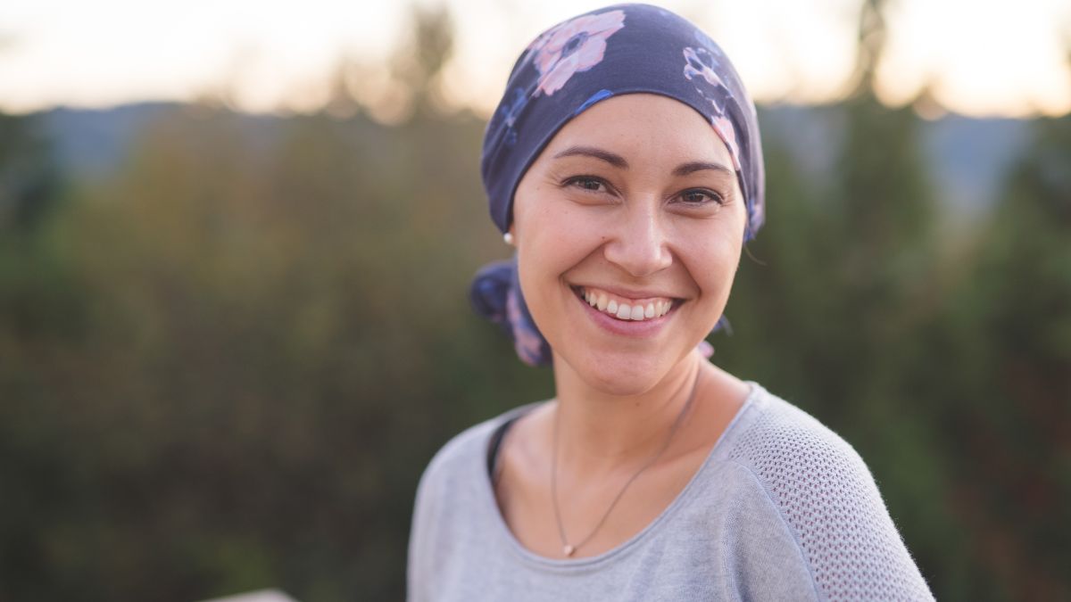 A Latina woman smiling, wearing a blue, floral headscarf