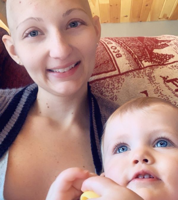 Kara Taylor, who has lost her hair as a side effect of chemo, holds her baby daughter joyfully.