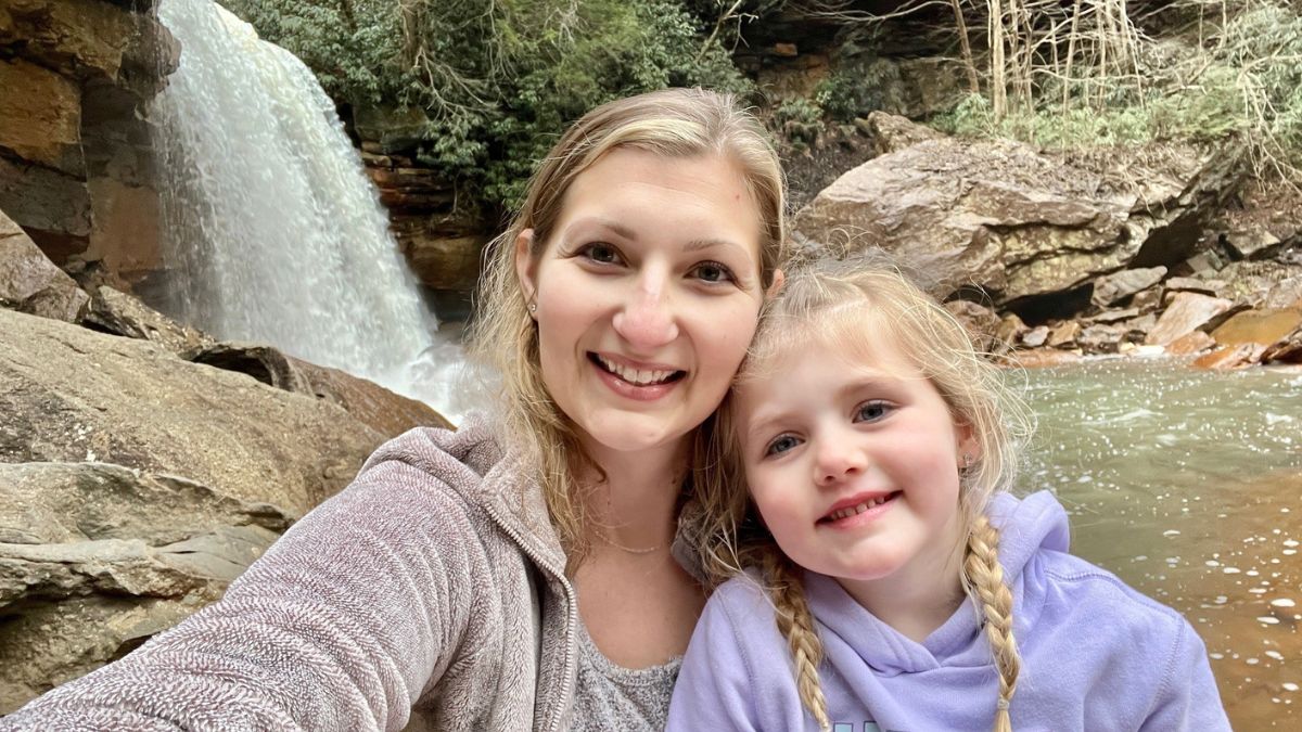 Kara Taylor and her daughter enjoy the beauty of nature together, a waterfall behind them.