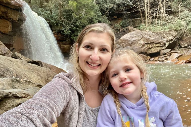 Kara Taylor and her daughter enjoy the beauty of nature together, a waterfall behind them.