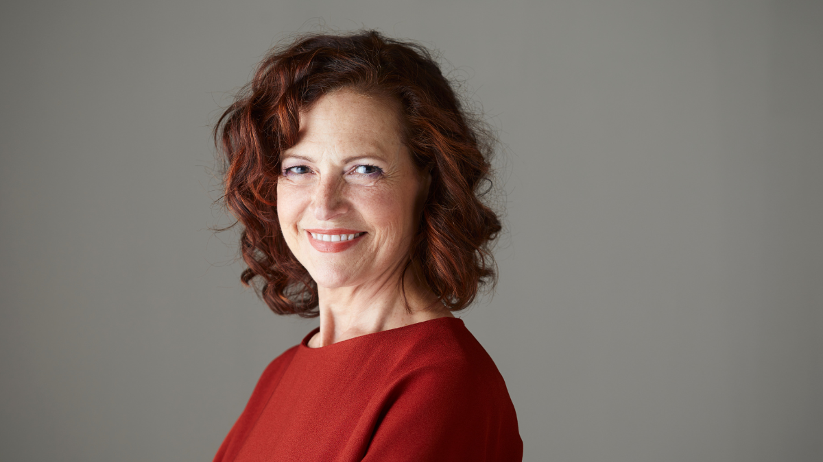 An older white woman wearing a red shirt, smiling