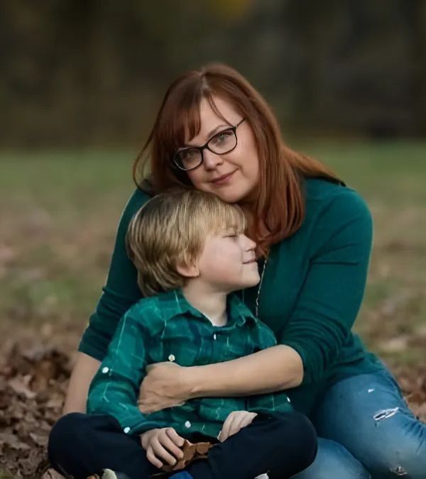 Charlotte Safrit holds her young son close in a loving embrace on a lovely fall day outdoors.
