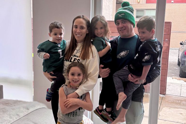 Marisa Berman, her husband, and four young children huddle together, wearing Eagles wear.