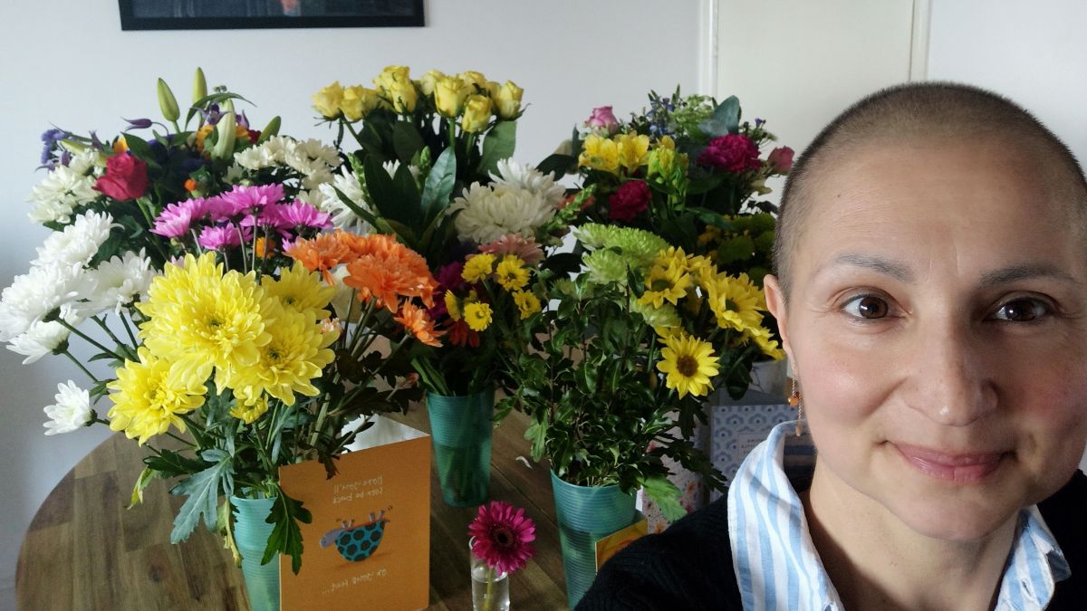 Virginia de Oliveira Marques stands in front of the many bouquets she has received for her breast cancer treatment.