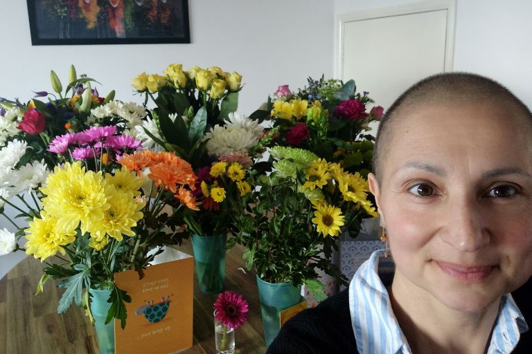 Virginia de Oliveira Marques stands in front of the many bouquets she has received for her breast cancer treatment.