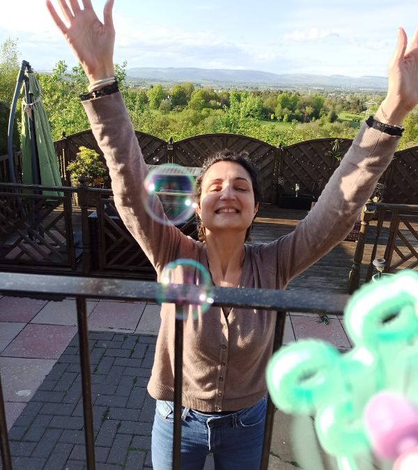 Virginia de Oliveira Marques raises her arms to catch the bubbles in the air.