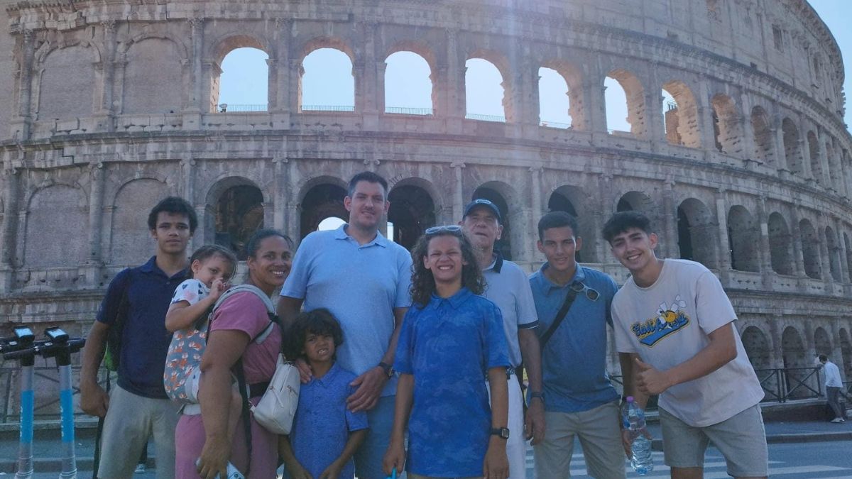 Angel Rinker, her husband, and their five children stand in front of the coliseum with two friends.