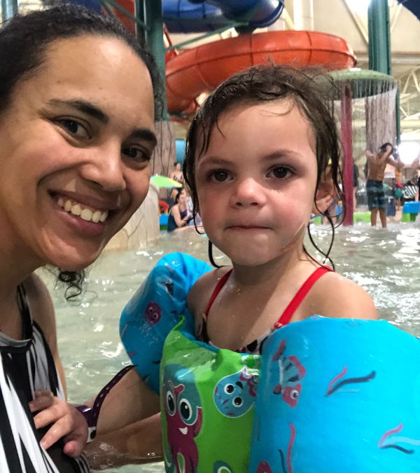 Angel Rinker holds her daughter, who wears floaters on her arms, in a water-park pool.