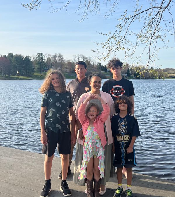 Angel Rinker stands surrounded by her children by a gorgeous lake.