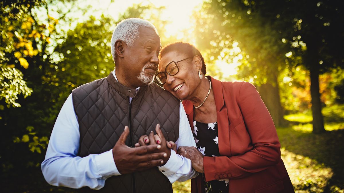 A older Black couple outside, the wife leaning on her husband.