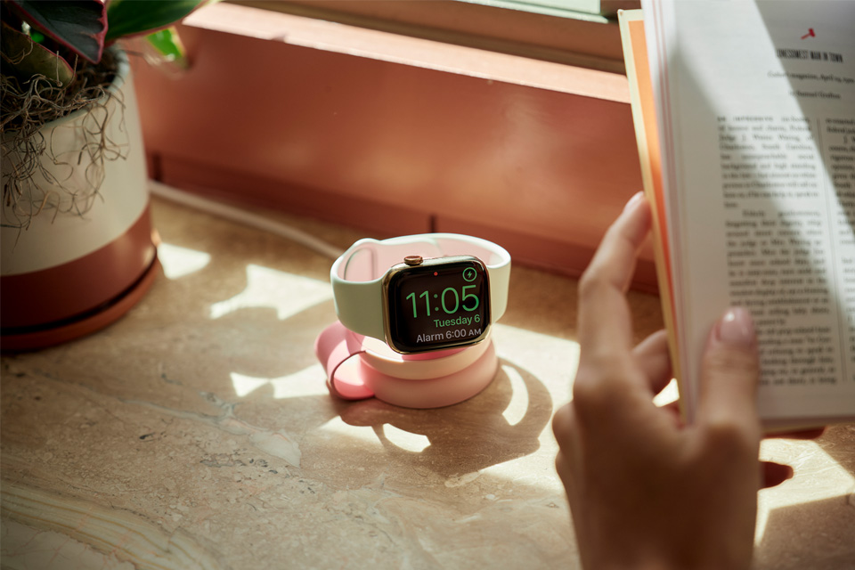 An apple watch sitting on the pink wireless charger