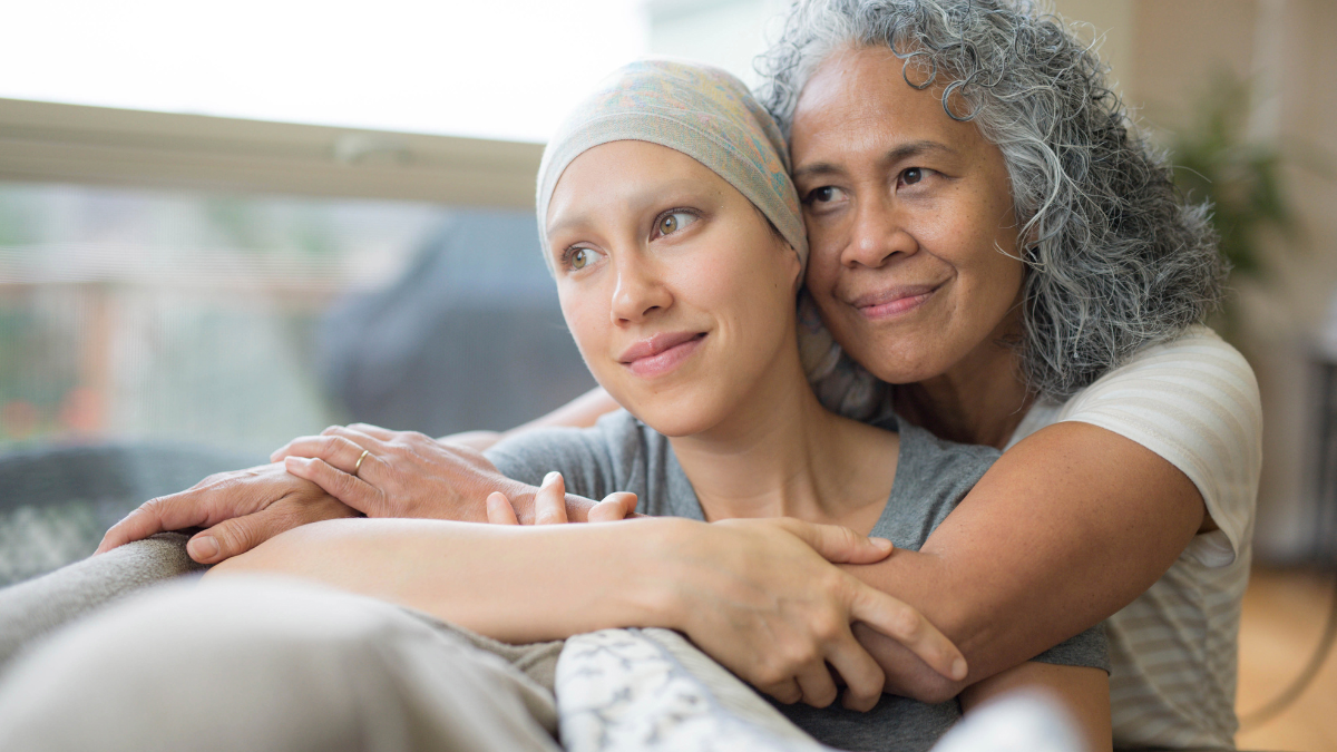 An older woman hugs a young woman with a headscarf