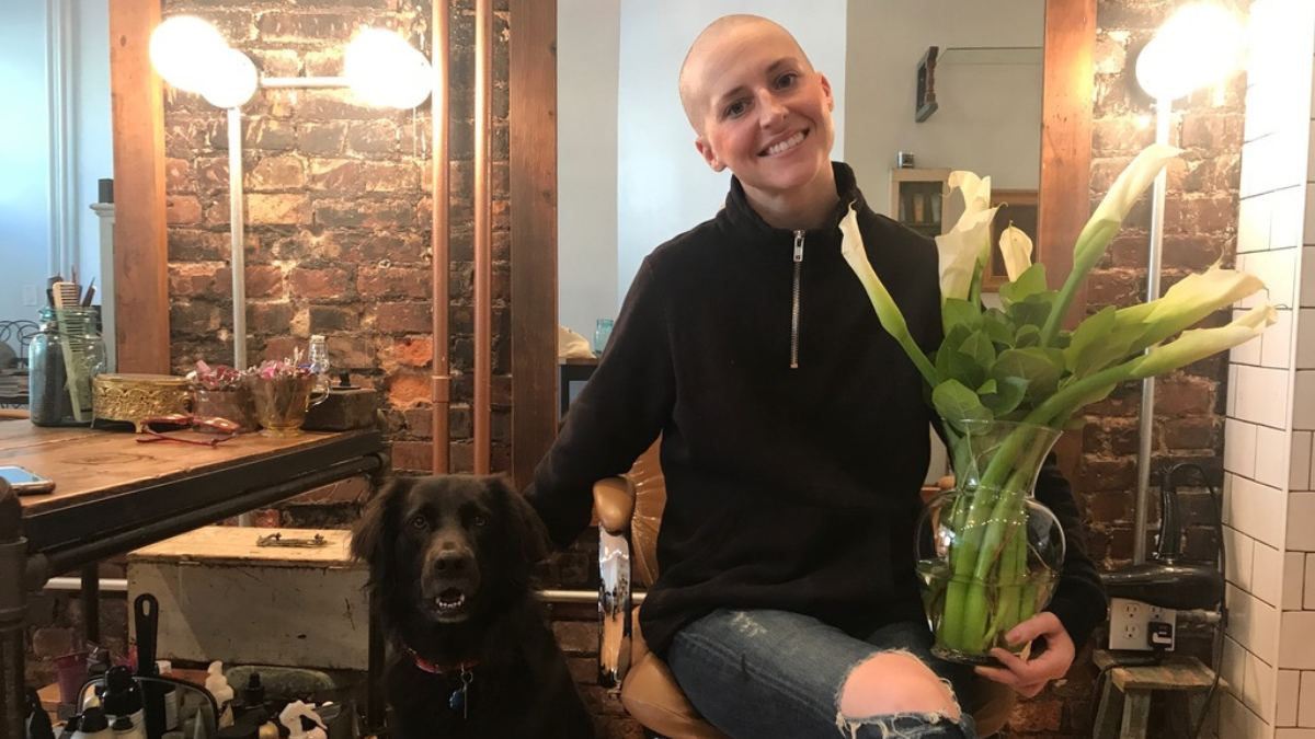 Chelsey smiling in her Brooklyn salon with a bald head.