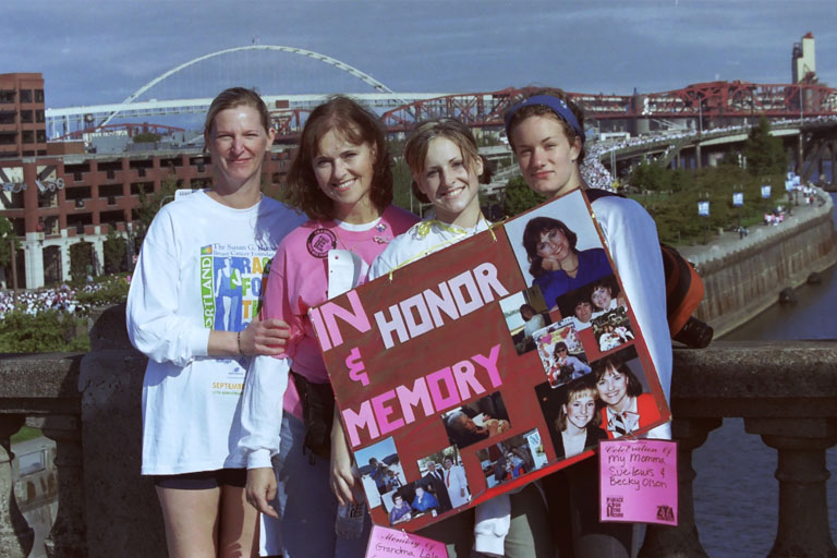Chelsey and her three friends holding up a poster that reads, "In honor & memory"