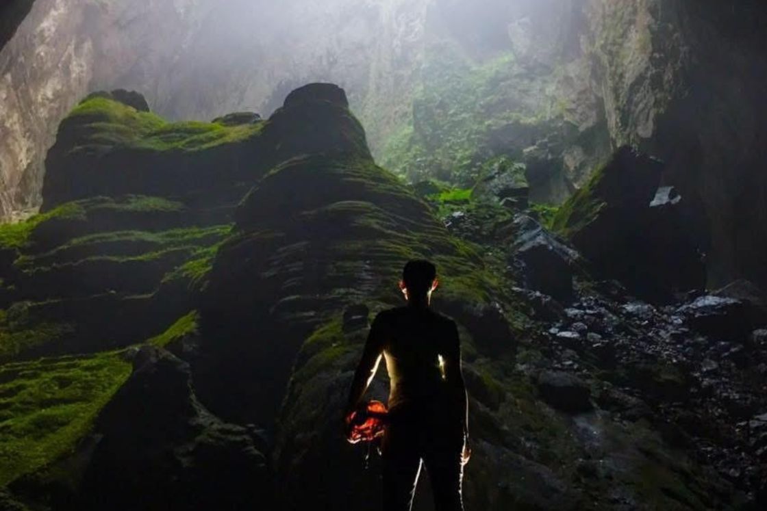 Courtney Bugler explores a beautiful cave, light streaming atop her.